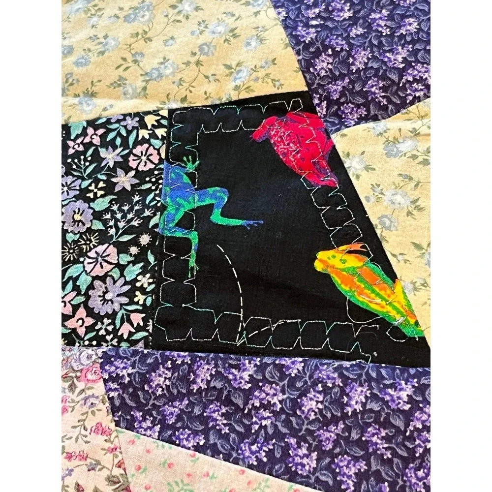 Black quilted wall hanging featuring colorful frogs 29x29